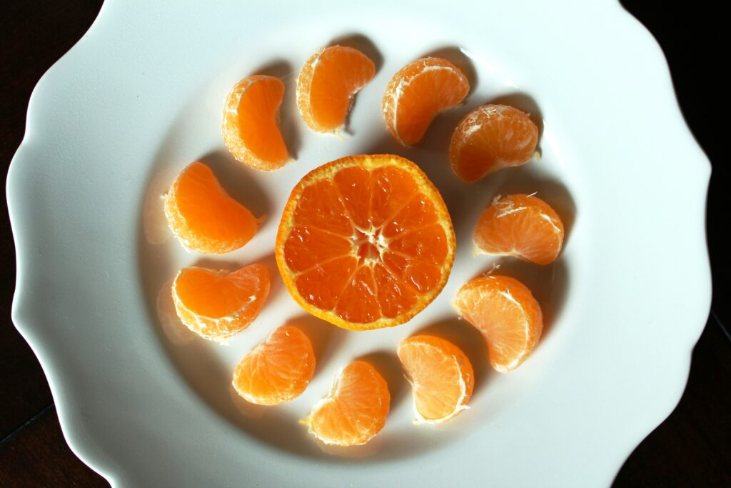 An orange sliced horizontally, encircled by segments of an orange to represent the fact that the different segments make up the orange.